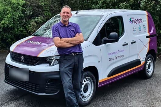 A Flotek engineer in a purple polo leaning against a white Flotek-branded van.